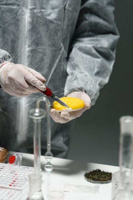 Scientist in protective gear handling samples with test tubes in a lab.